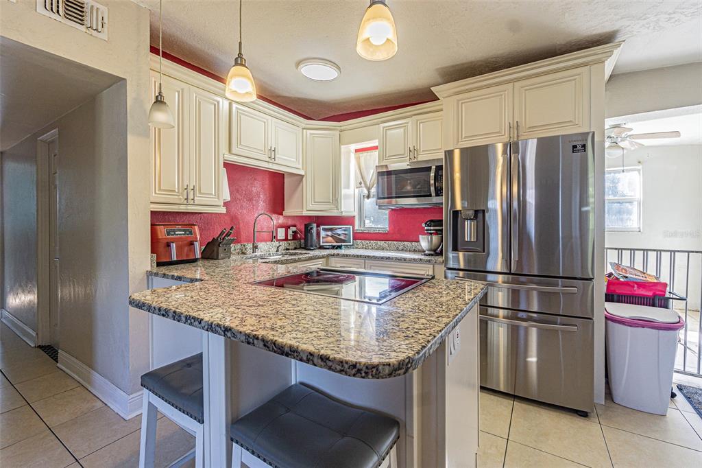 9696 Groveland Street Seminole, FL 33772 - Photo 5 of 22 a kitchen with stainless steel appliances granite countertop a sink refrigerator and microwave