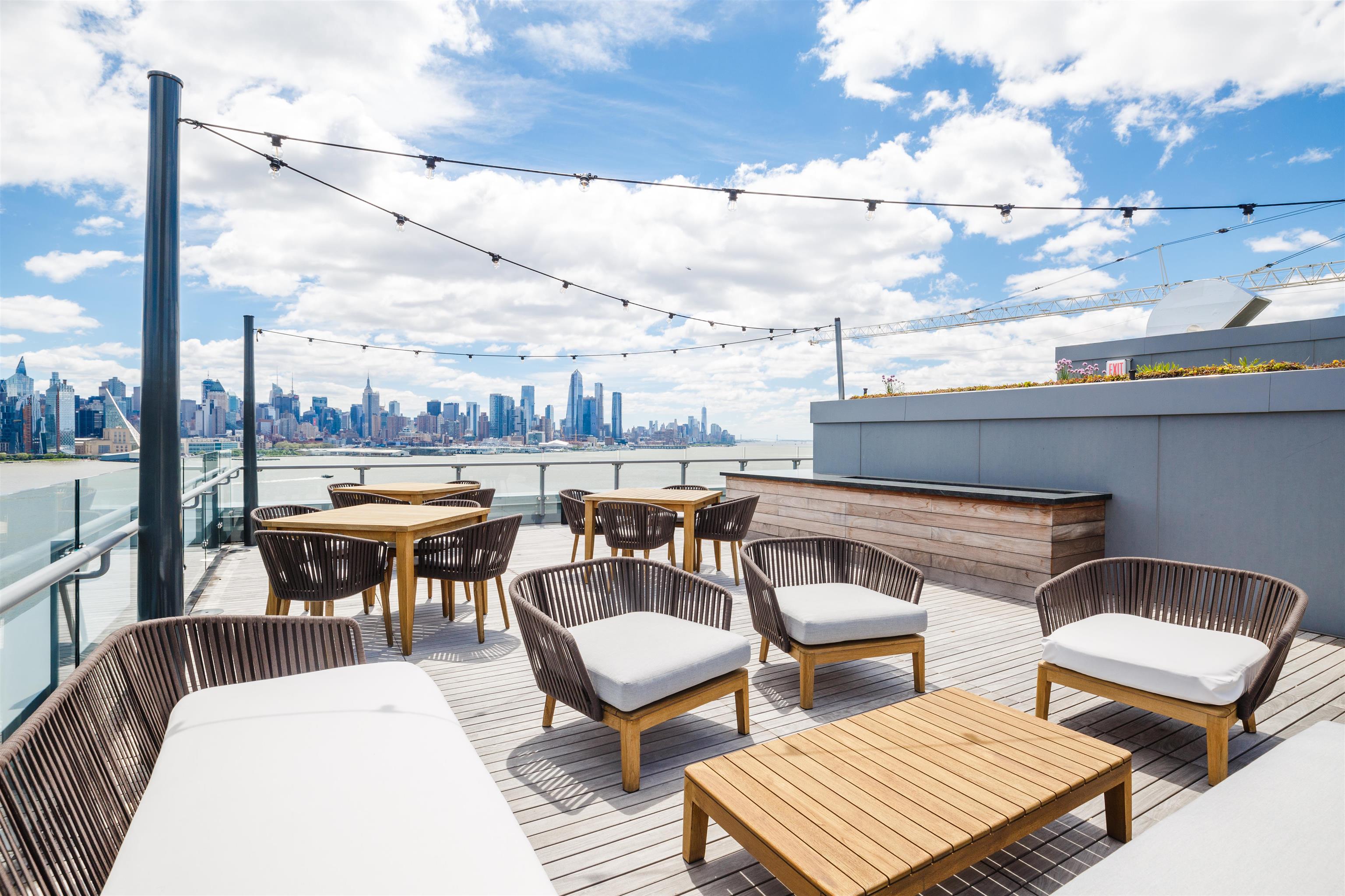 9 Ave At Port Imperial, Unit 925 West New York, NJ 07093 - Photo 12 of 14 a balcony with wooden benches and a couch