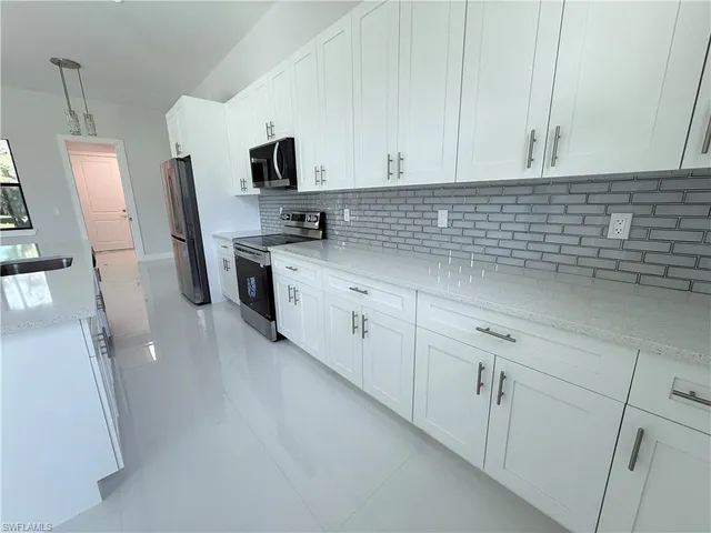 a kitchen with stainless steel appliances granite countertop a refrigerator a stove a sink a microwave and a refrigerator