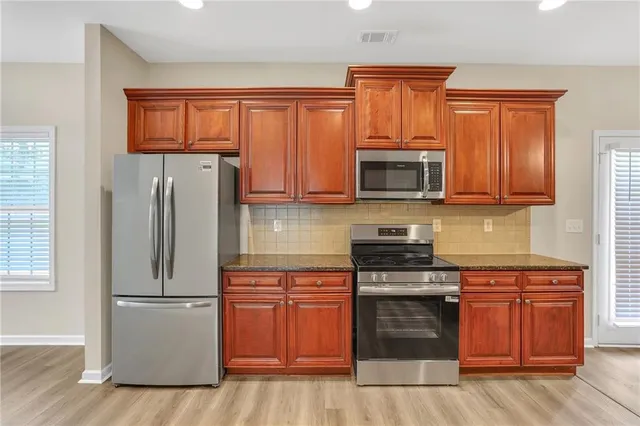 a kitchen with granite countertop wooden cabinets and stainless steel appliances
