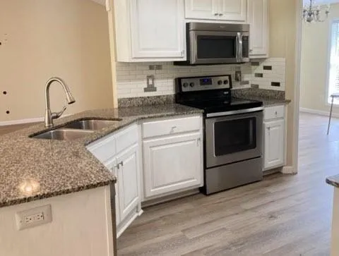 a kitchen with granite countertop a sink stove and microwave