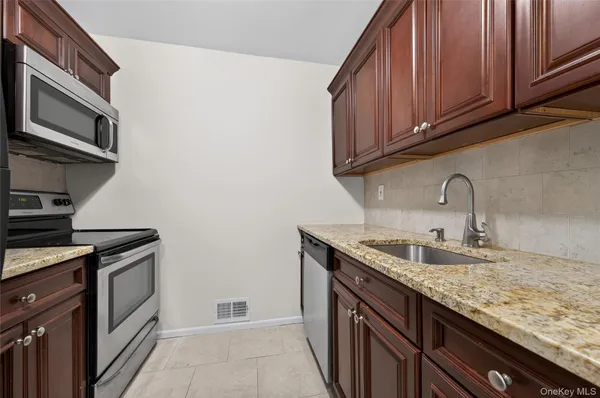 a kitchen with granite countertop a sink stove and cabinets