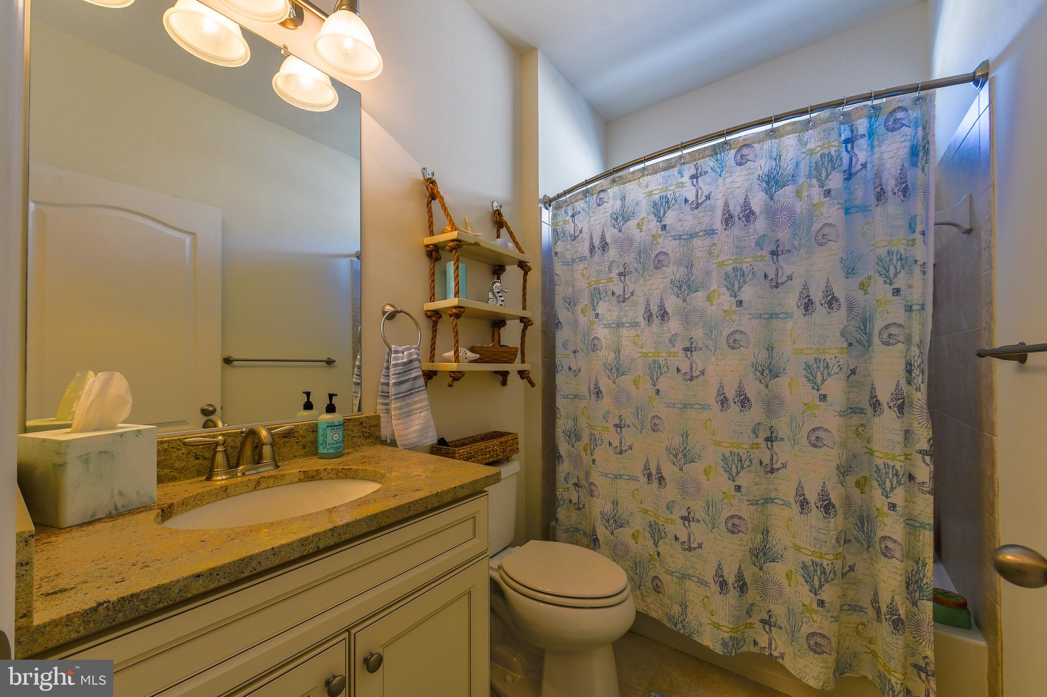 34148 Spring Brook Avenue Lewes, DE 19958 - Photo 32 of 77 a bathroom with a granite countertop sink a toilet and a mirror