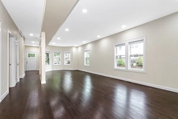 an empty room with wooden floor and windows