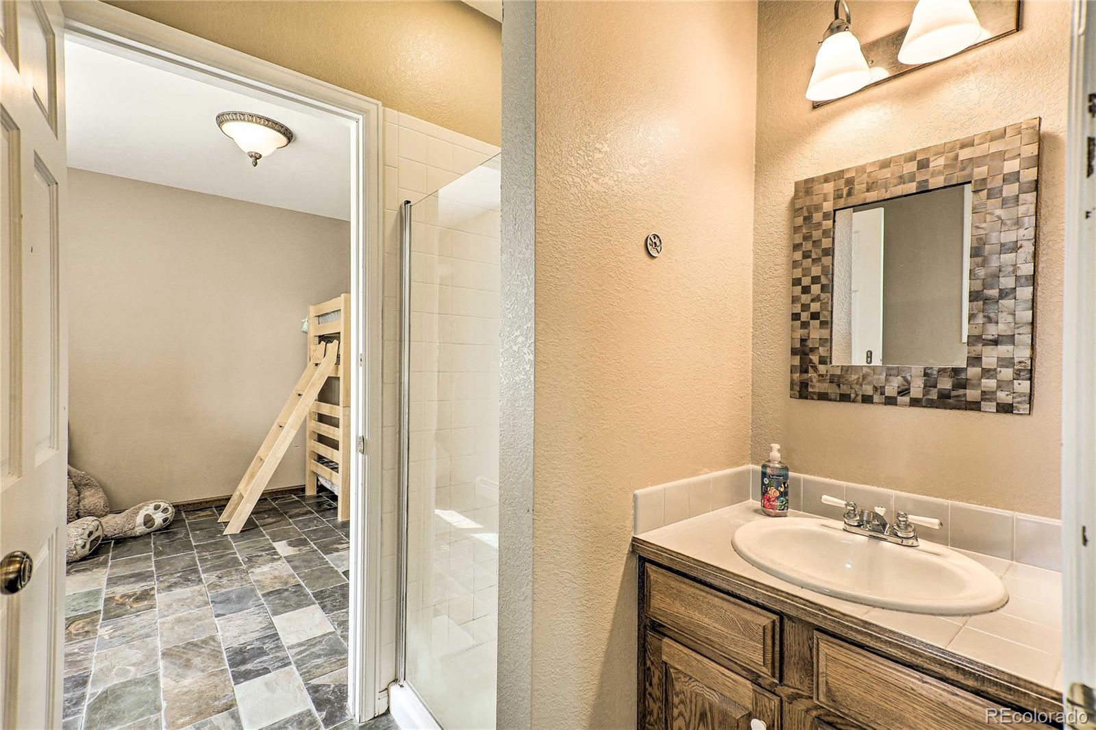 345 Old Sawmill Road Bailey, CO 80421 - Photo 24 of 39 a bathroom with a granite countertop sink a mirror and a shower