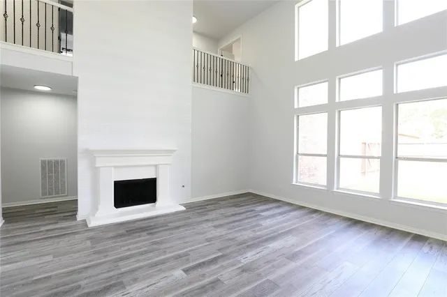 an empty room with wooden floor fireplace and windows