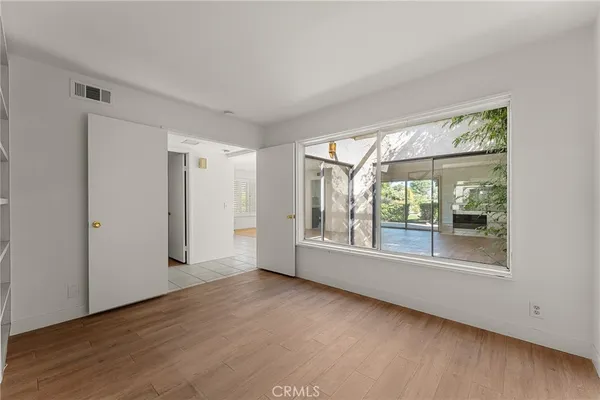 an empty room with wooden floor and windows