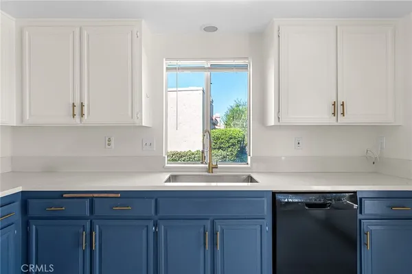 a kitchen with stainless steel appliances granite countertop white cabinets sink and a window