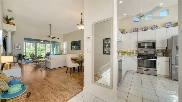 a living room with stainless steel appliances furniture and a kitchen view