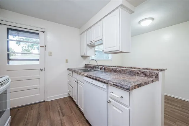 a kitchen with white cabinets and a wooden floor