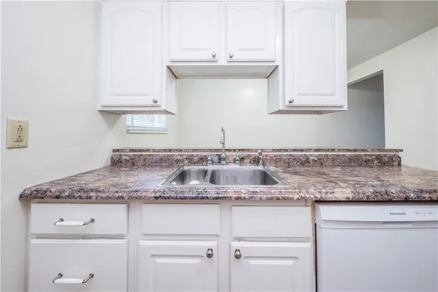 a kitchen with granite countertop white cabinets and a sink