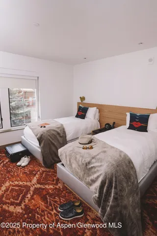 a bedroom with two beds and a large window