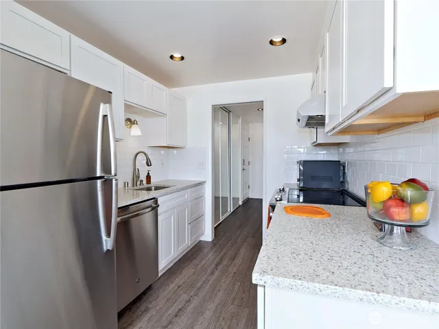 a kitchen with stainless steel appliances granite countertop a refrigerator a stove and a sink