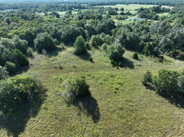 an aerial view of residential house with outdoor space and trees all around