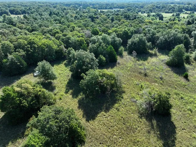 an aerial view of residential house with outdoor space and trees all around