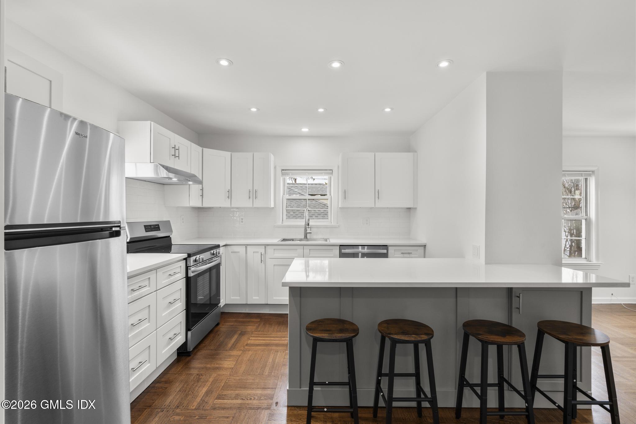 134 River Rd Extension, Unit 2 Cos Cob, CT 06807 - Photo 5 of 19 a kitchen with granite countertop white cabinets and stainless steel appliances