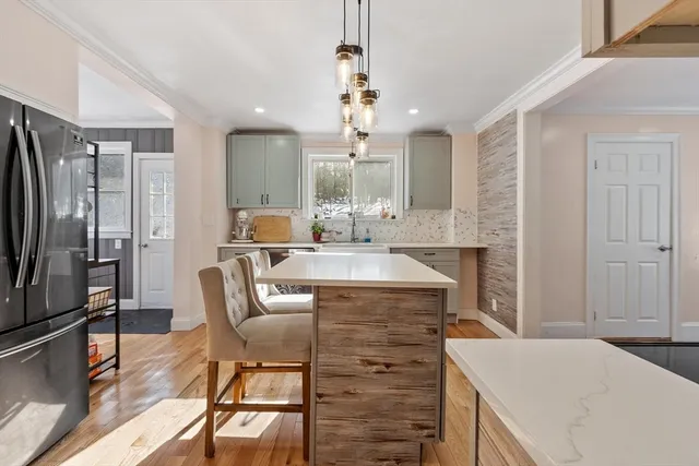 a kitchen with stainless steel appliances granite countertop a table chairs and a refrigerator