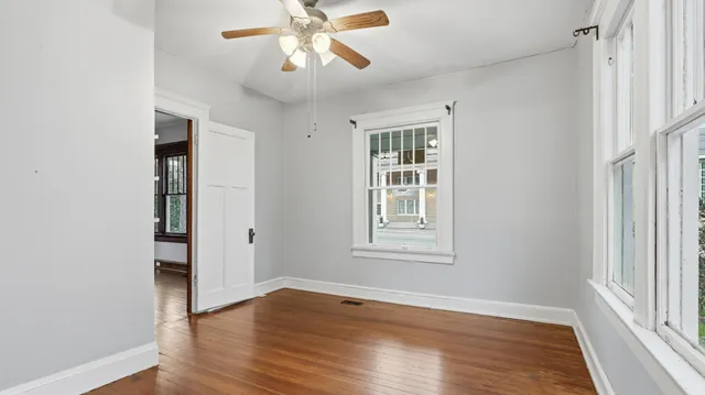 an empty room with wooden floor closet and windows