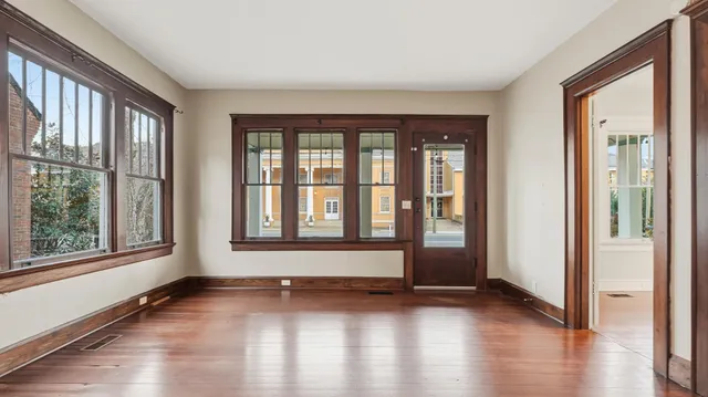 a view of an empty room with wooden floor and a window