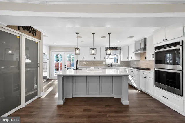 a large white kitchen with stainless steel appliances kitchen island granite countertop a stove and a sink