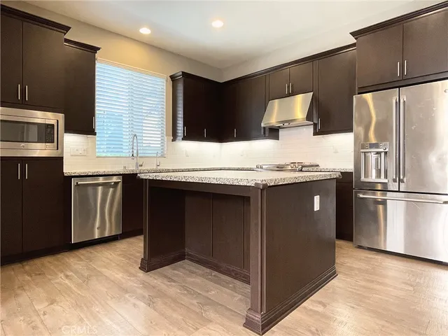 a kitchen with stainless steel appliances granite countertop a stove a refrigerator and a sink