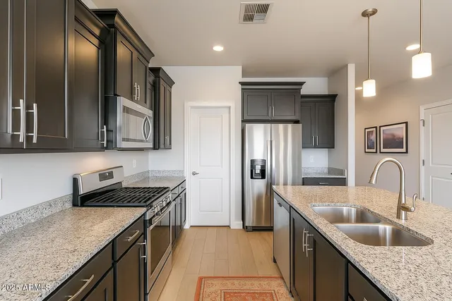 a kitchen with granite countertop stainless steel appliances a sink stove and refrigerator