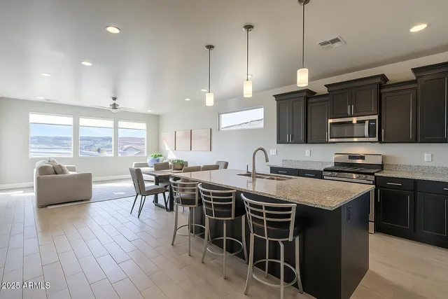 a kitchen with stainless steel appliances granite countertop a stove a sink a microwave a dining table and chairs with wooden floor