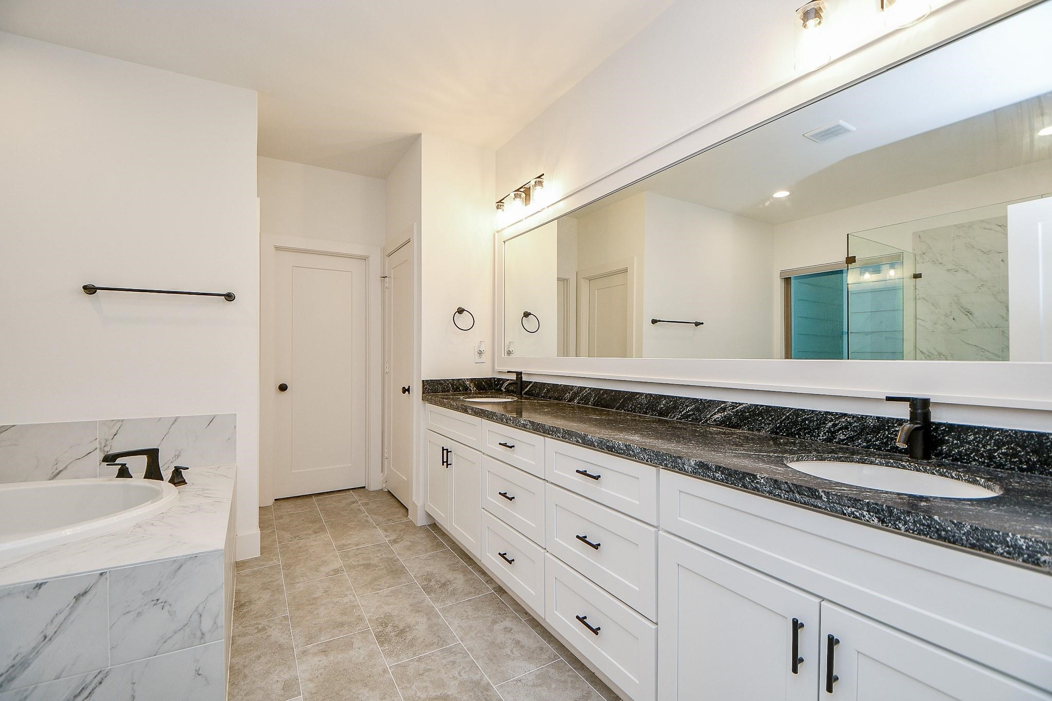 4403 Greeley Street Houston, TX 77006 - Photo 18 of 28 a bathroom with a granite countertop double vanity sink a mirror and a bathtub