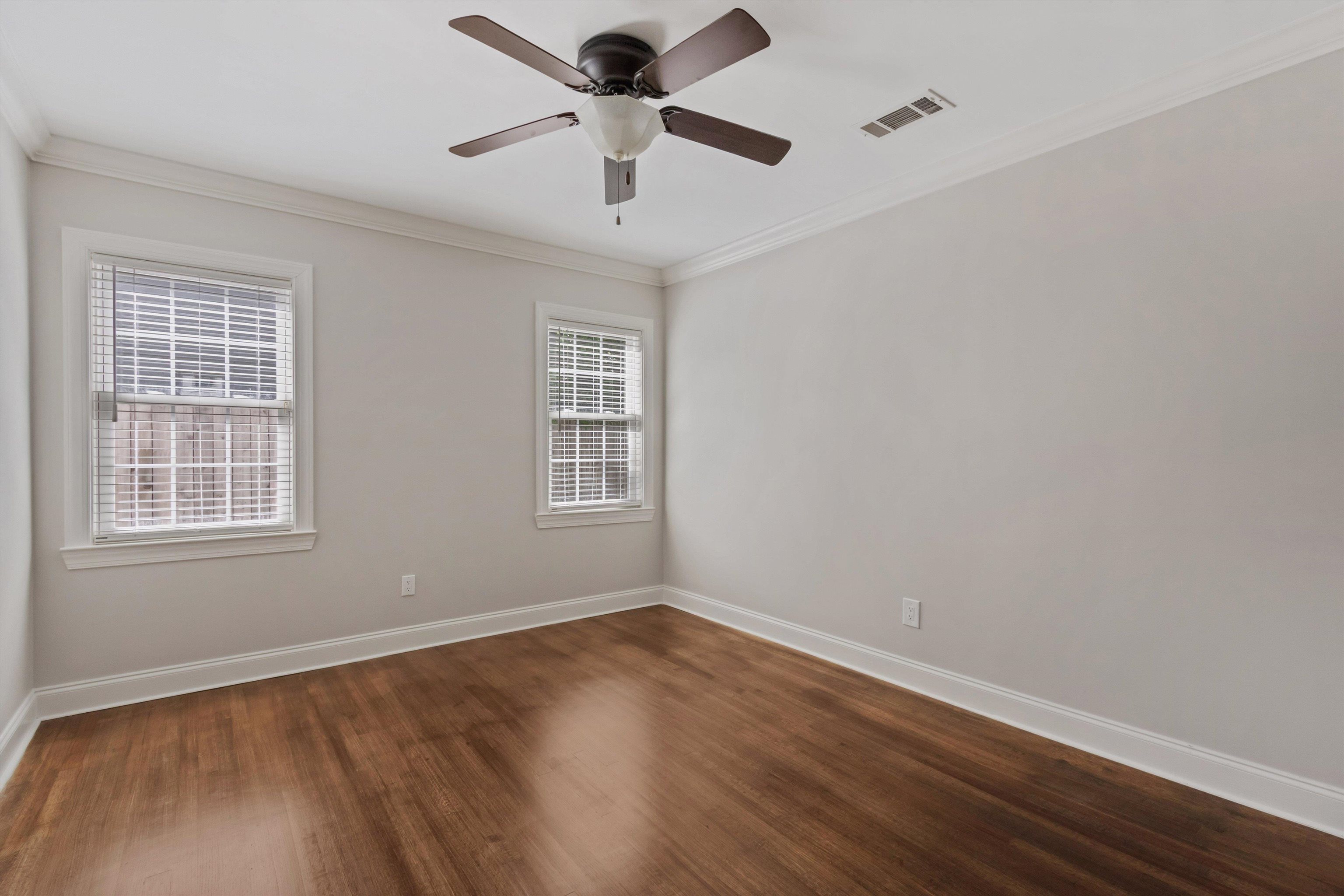 5302 South Angela Road Memphis, TN 38120 - Photo 26 of 40 Room featuring wood-finish flooring, two large windows with blinds, a ceiling fan, crown molding, and neutral wall paint