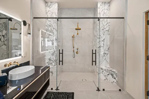 a bathroom with a granite countertop shower a sink and a mirror