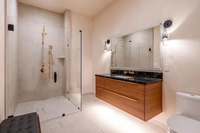 a bathroom with a granite countertop sink a toilet and shower