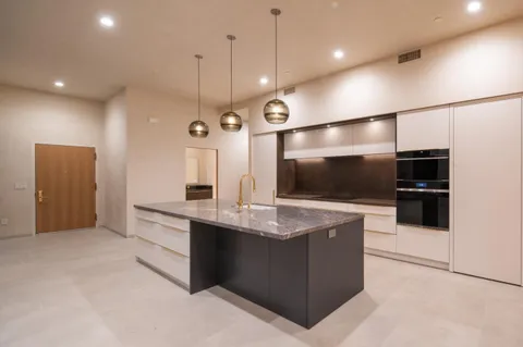 a large kitchen with a large counter top a refrigerator and a sink