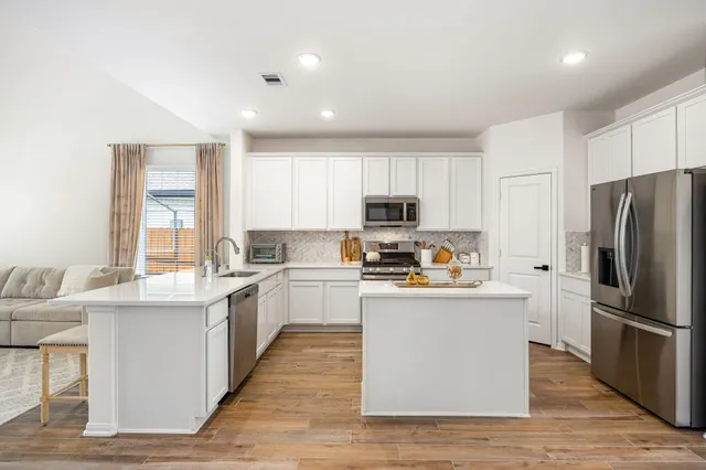 a kitchen with stainless steel appliances a refrigerator a stove top oven and a center island with wooden floor