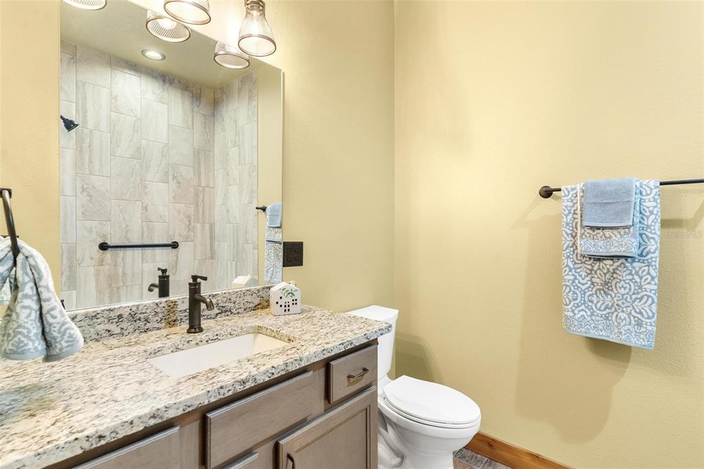37590 Rolling Acres Road Lady Lake, FL 32159 - Photo 21 of 30 a bathroom with a granite countertop sink a toilet and a mirror
