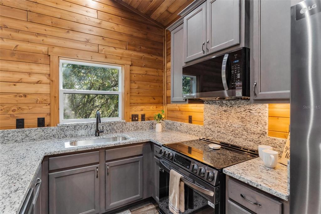 37590 Rolling Acres Road Lady Lake, FL 32159 - Photo 10 of 30 a kitchen with granite countertop a sink a stove and cabinets