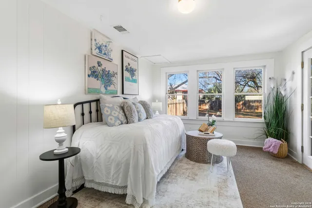 a spacious bedroom with a bed and a painting on the wall