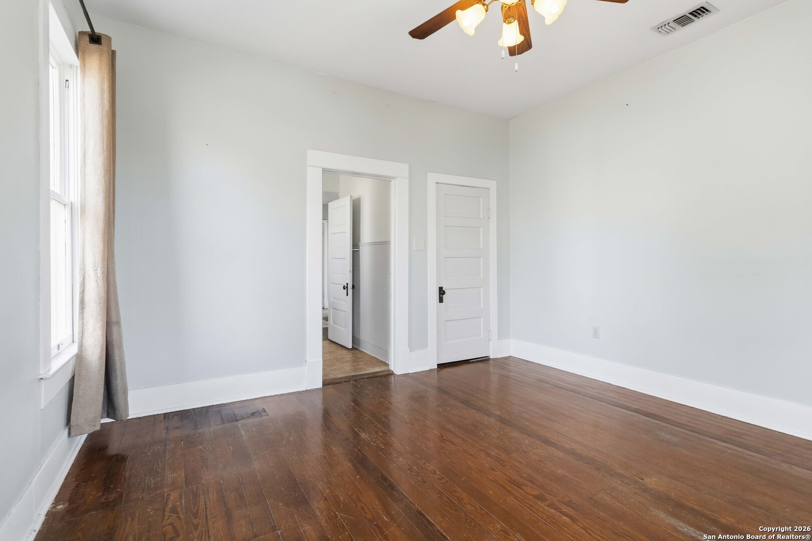 1409 21st Street Hondo, TX 78861 - Photo 22 of 25 an empty room with wooden floor chandelier fan and windows