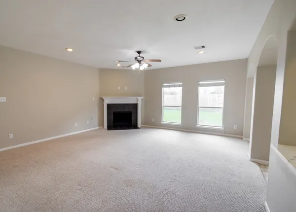an empty room with windows and fireplace