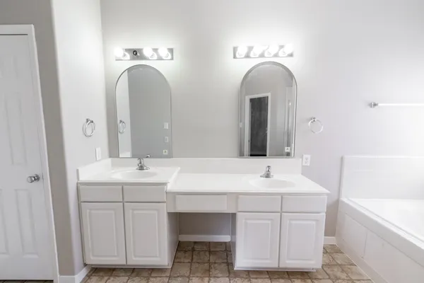a bathroom with a double vanity sink mirror and bathtub