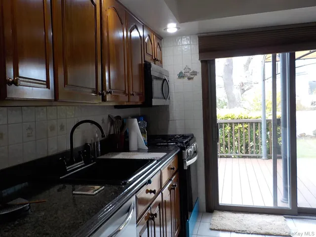 a kitchen with granite countertop stainless steel appliances a sink stove and cabinets