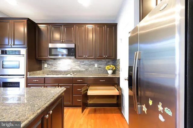 a kitchen with kitchen island granite countertop a refrigerator a stove and a sink