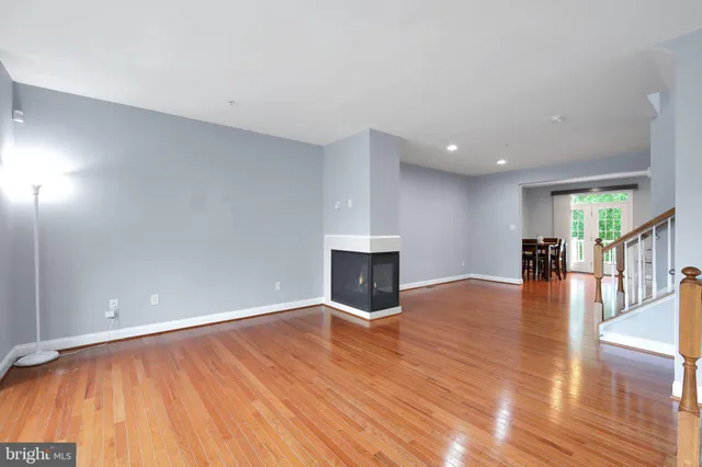 a view of a livingroom with wooden floor and a kitchen