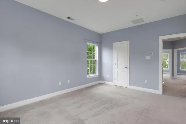 a view of an empty room with window and bathroom