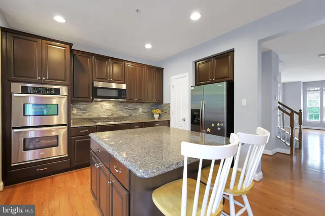 a kitchen with stainless steel appliances granite countertop wooden cabinets dining table and chairs