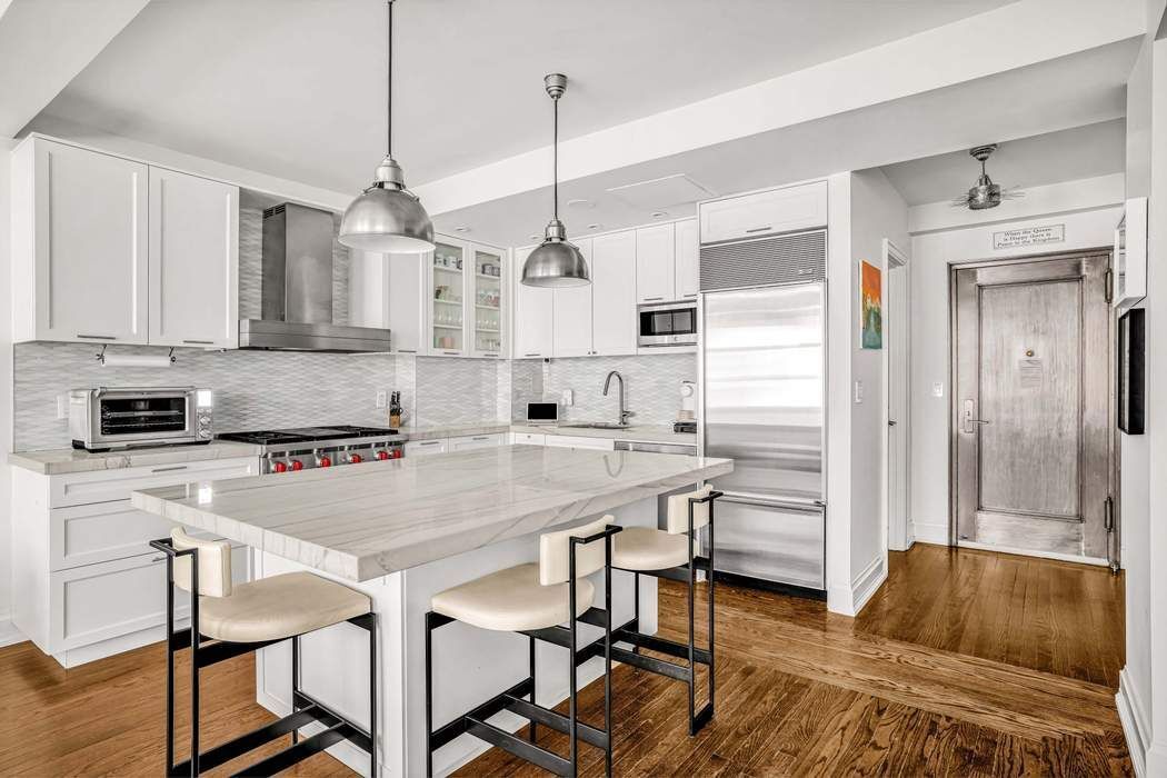 470 West 24th Street, Unit 7GJ Manhattan, NY 10011 - Photo 2 of 11 a kitchen with stainless steel appliances a stove a sink a refrigerator a center island a table and chairs