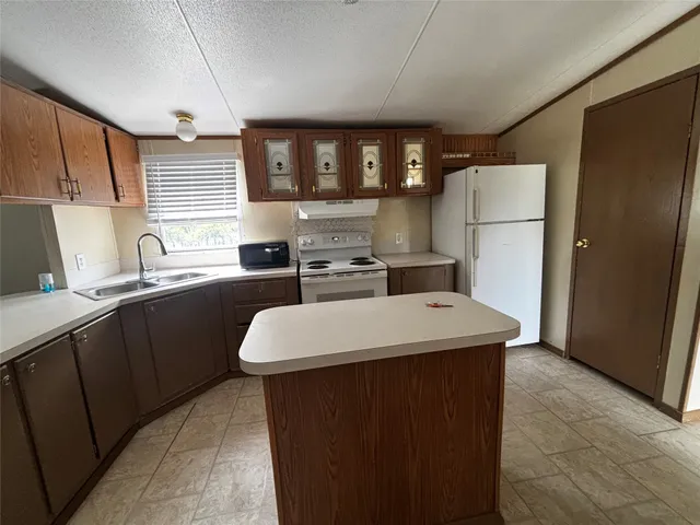 a kitchen with stainless steel appliances a sink a refrigerator a counter top space and cabinets