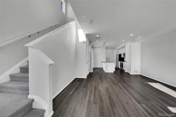 a view of a living room with wooden floor and stairs