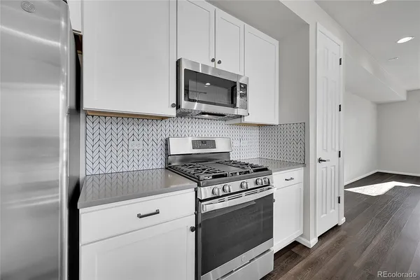 a kitchen with stainless steel appliances white cabinets and a stove top oven