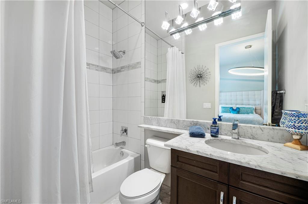 4462 Caldera Circle Naples, FL 34119 - Photo 24 of 33 a bathroom with a granite countertop sink a toilet a mirror and shower