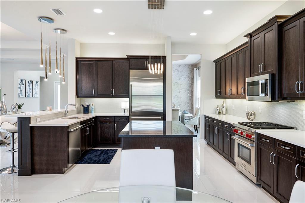 4462 Caldera Circle Naples, FL 34119 - Photo 8 of 33 a large kitchen with stainless steel appliances granite countertop a sink stove and refrigerator